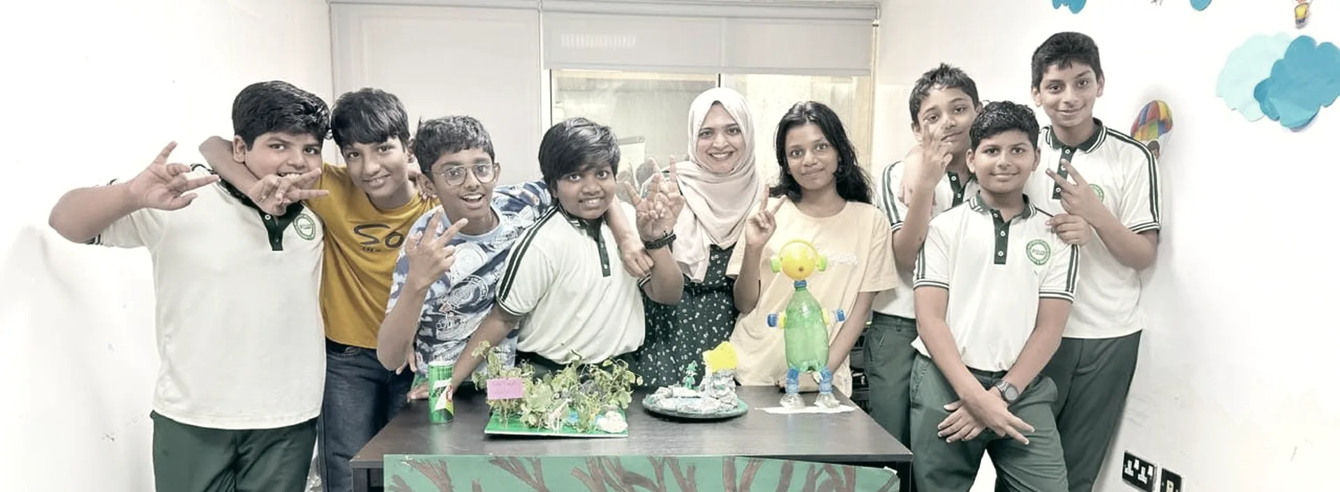 Students at PHLOEM Learning in Abu Dhabi standing with a recycling project they built together