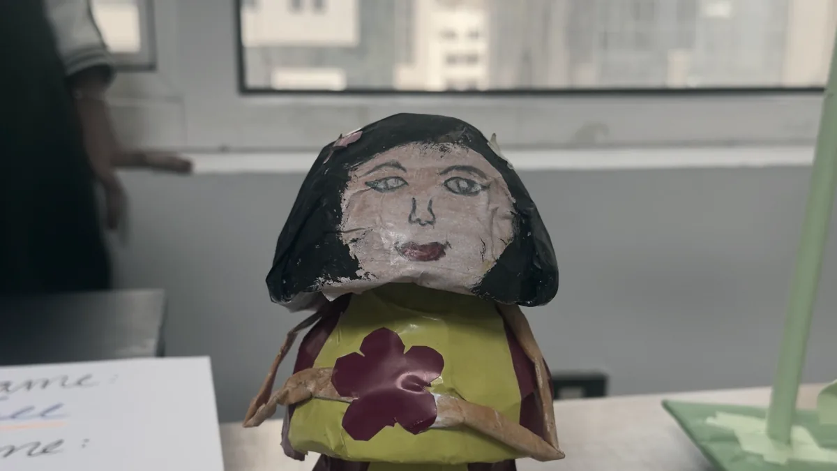 A painted figure made by a student at PHLOEM Junior Creative Lab, standing on a desk