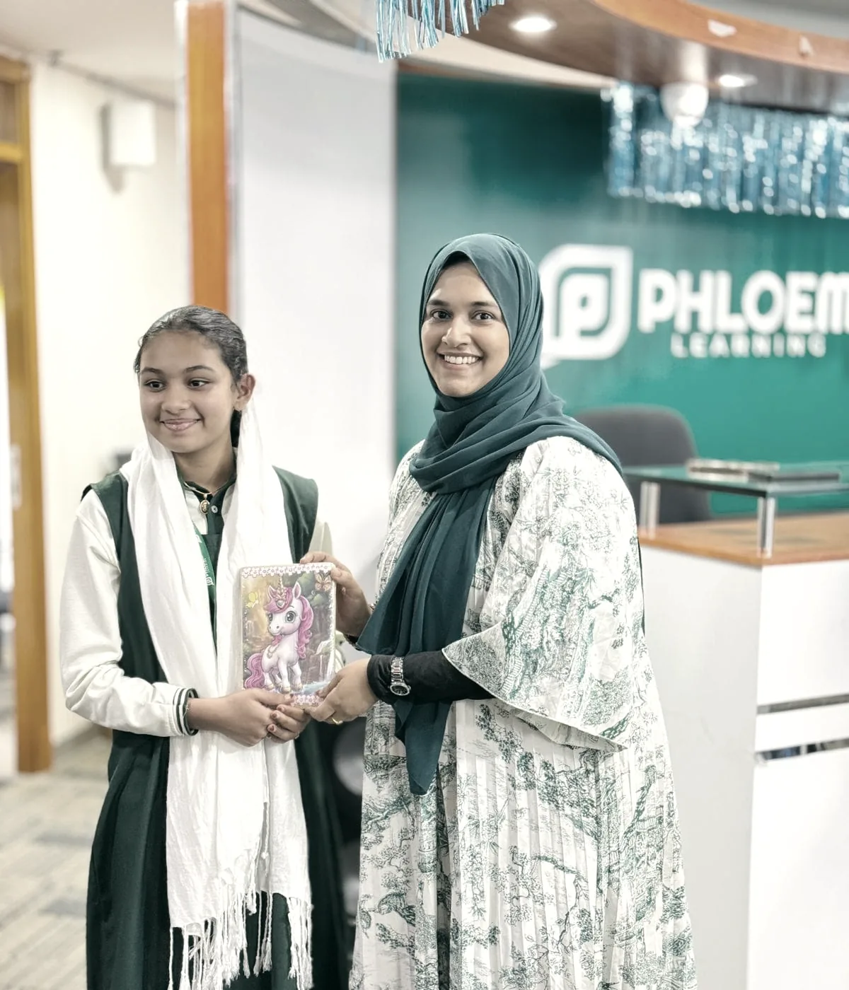 A student receiving her finished work from her tutor at PHLOEM Learning in Abu Dhabi