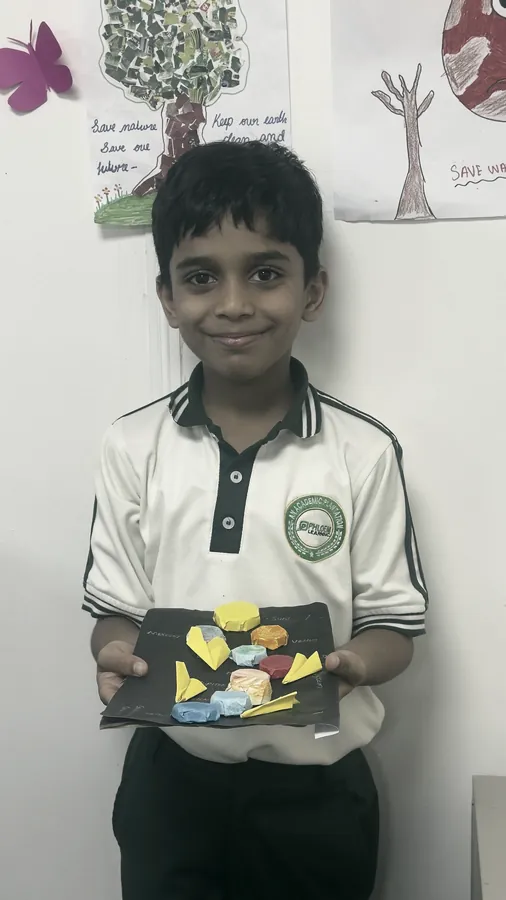 A student holding a paper collage he cut and laid by hand