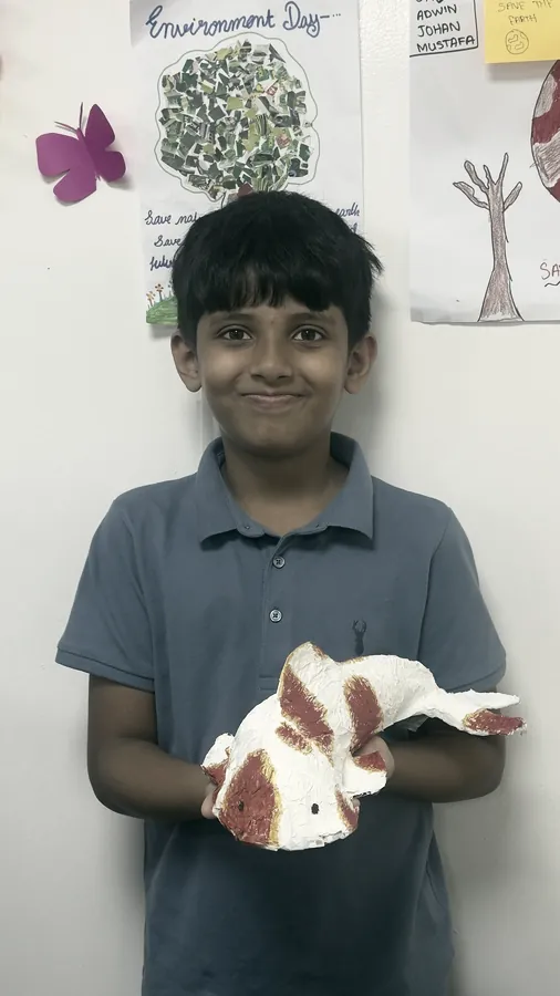 A student holding a painted fish he made for Environment Day at PHLOEM Learning
