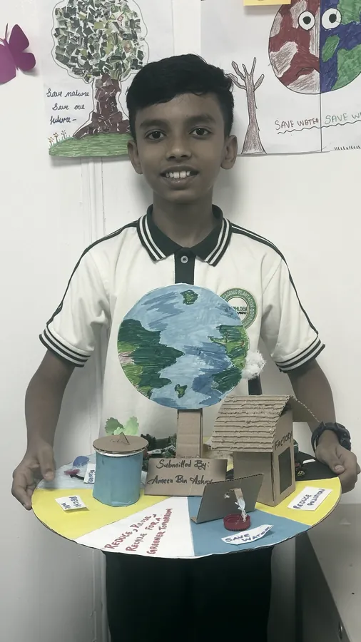 A student holding a model of a house and garden mounted on a painted board